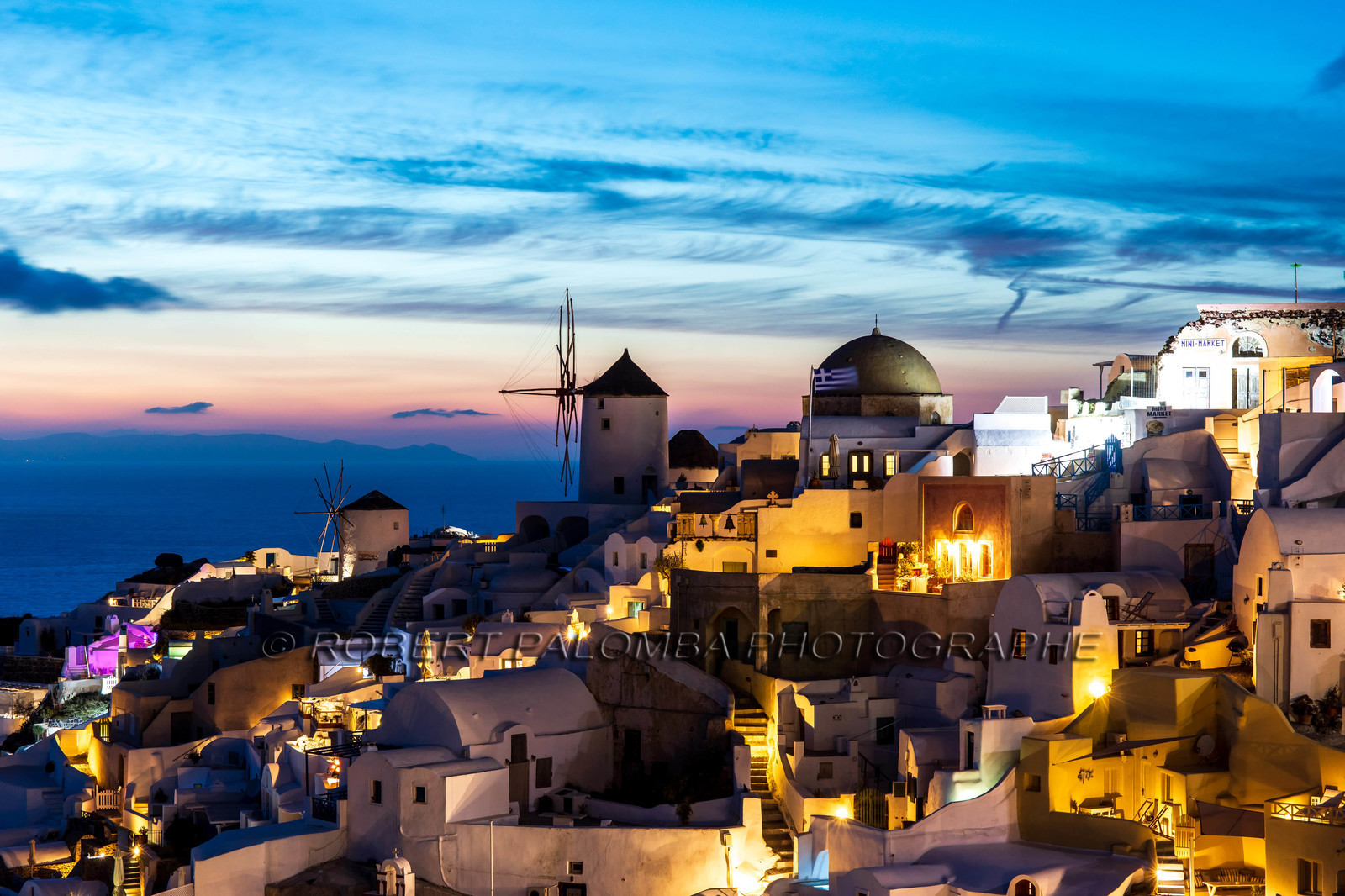 Grèce, Cyclades, Santorin, Santorin est l'une des îles des Cyclades, dans la mer Égée. Elle a été détruite par une éruption volcanique au XVIe siècle av. J.-C., qui a définitivement façonné ses paysages accidentés. Les maisons blanches en forme de cube de ses 2 villes principales, Fira et Oia, sont accrochées sur des falaises surplombant une caldeira (cratère) sous-marine. Elles dominent la mer, des petites îles à l'ouest ainsi que des plages composées de galets de lave noirs, rouges et blancs.